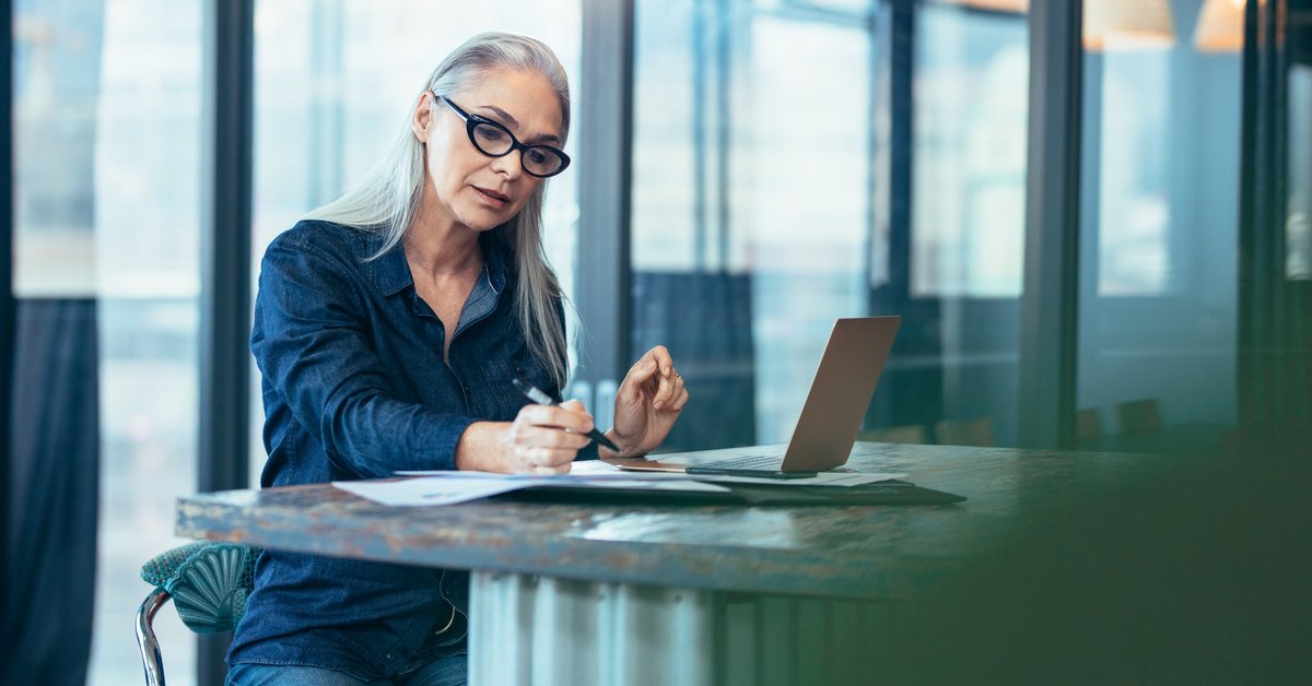 A woman reading paperwork at a desk.