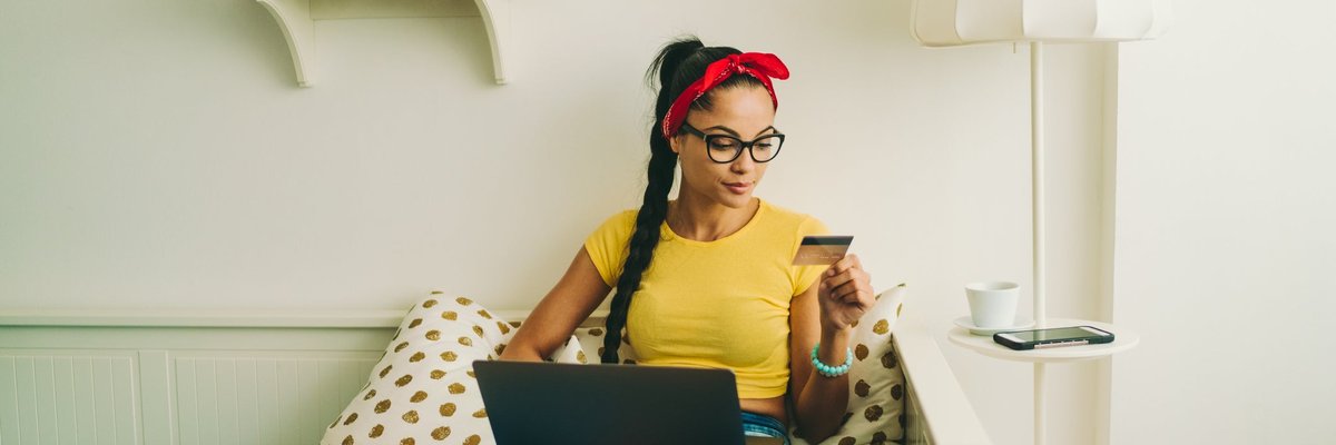 Woman relaxing at home looking at a credit card in her hand.
