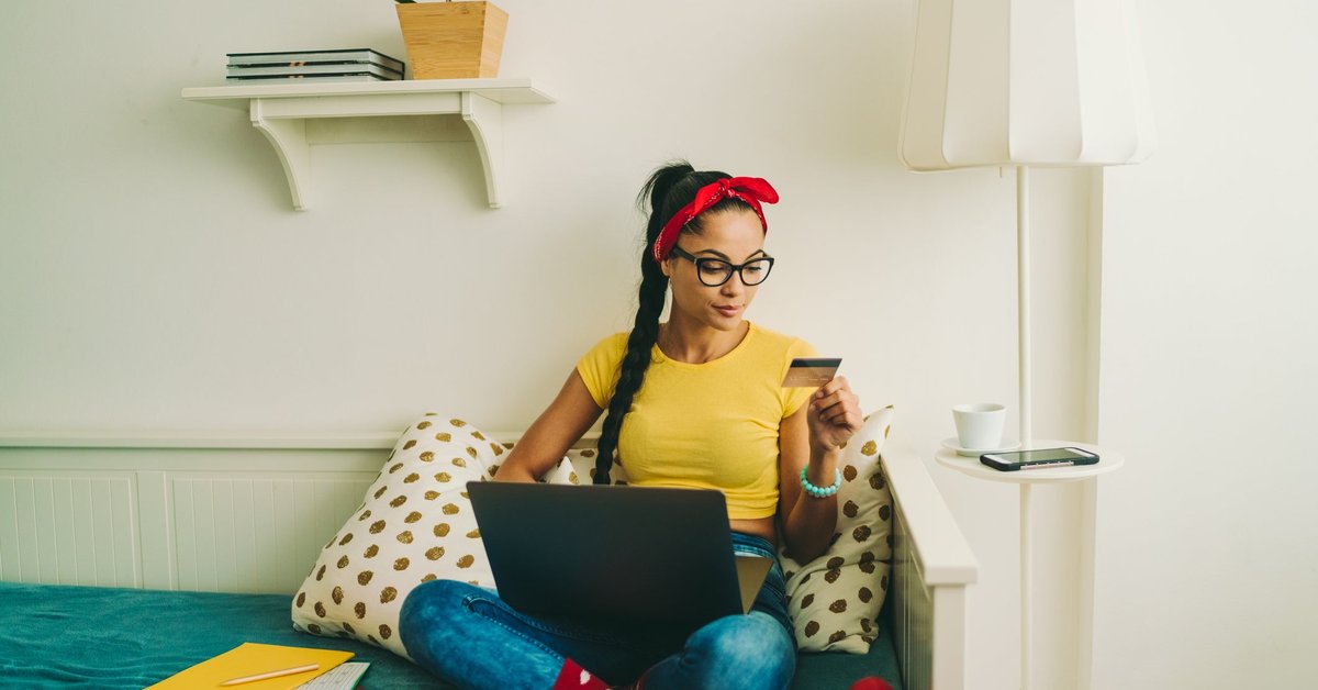 Woman relaxing at home looking at a credit card in her hand.
