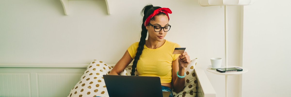 Woman relaxing at home looking at a credit card in her hand.