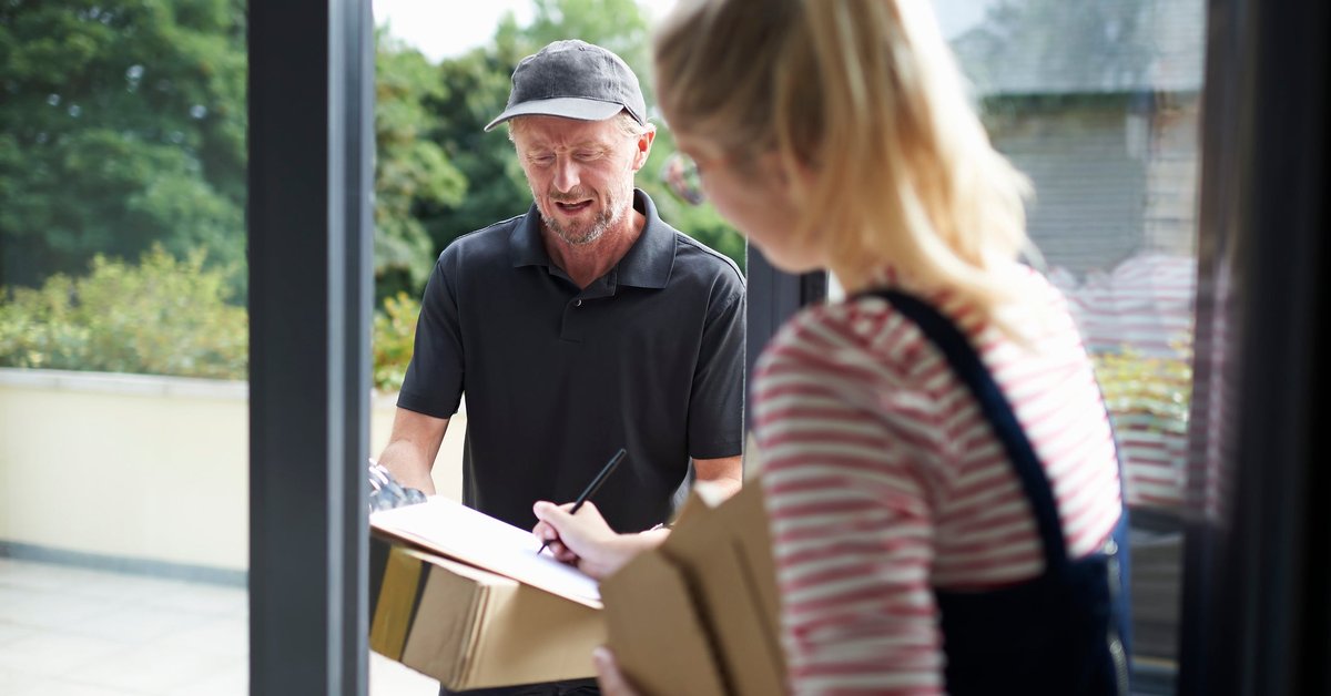 Woman signing for packages with a delivery person.