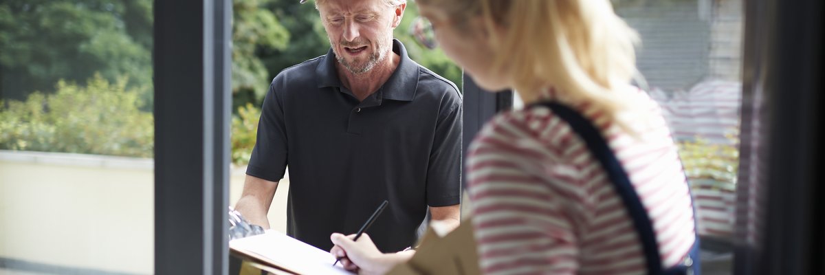 Woman signing for packages with a delivery person.