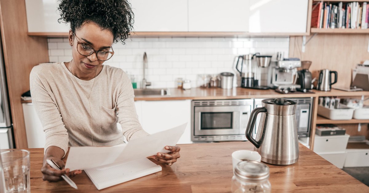 A woman sits in her kitchen, going over her personal finances.