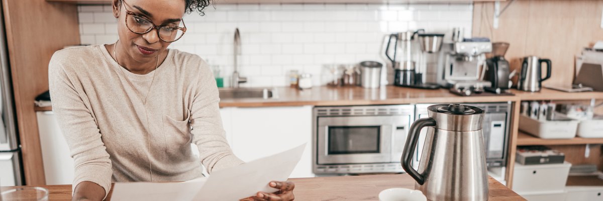 A woman sits in her kitchen, going over her personal finances.