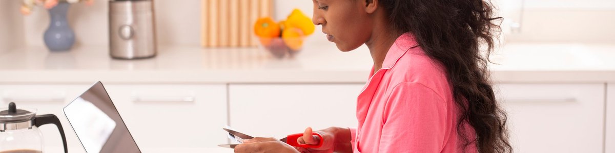 Woman sitting in front of her laptop cutting up a credit card.