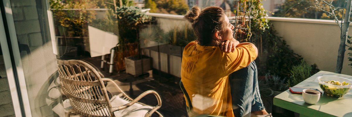 Woman sitting outside on her condo balcony.