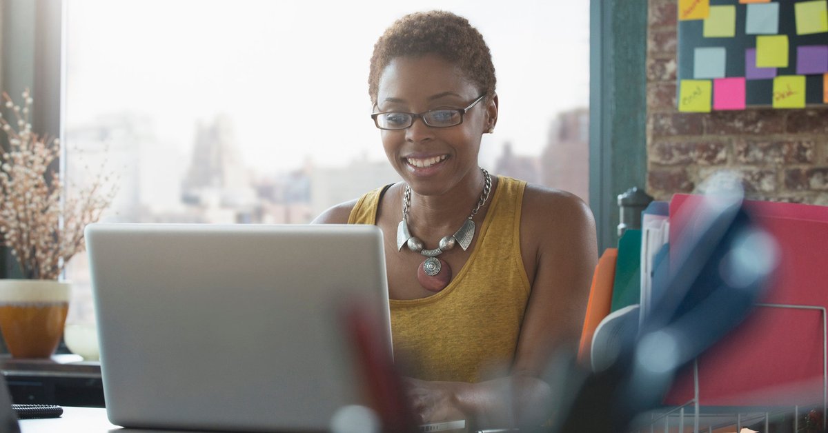 Woman smiling as she uses her laptop.