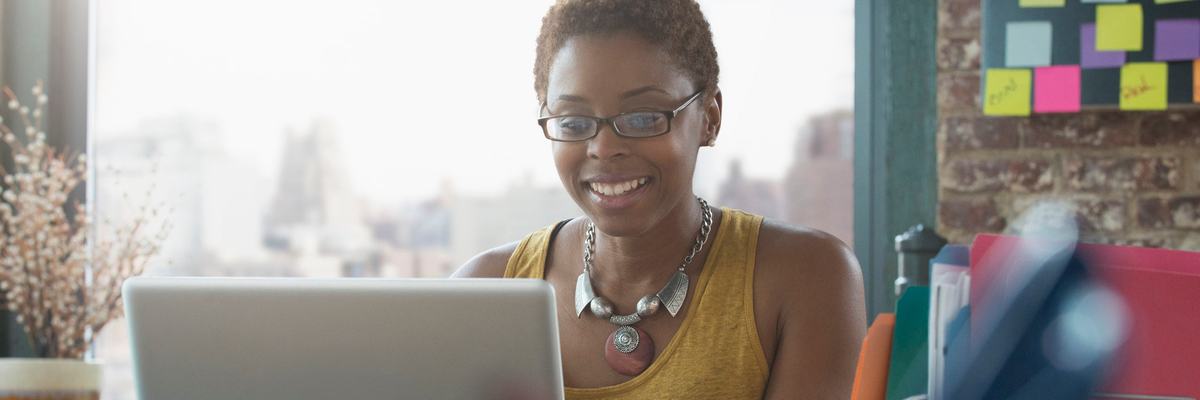 Woman smiling as she uses her laptop.