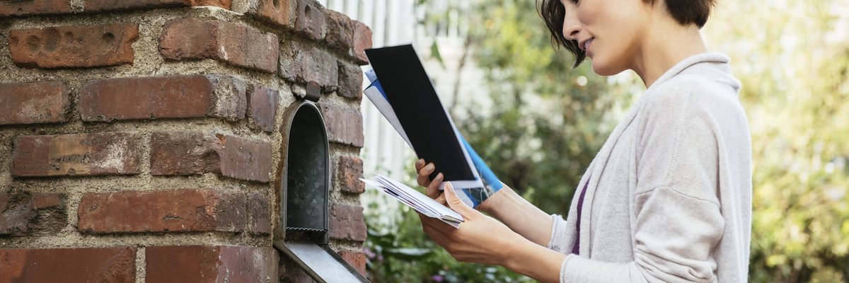 Woman sorting through mail at her mailbox.