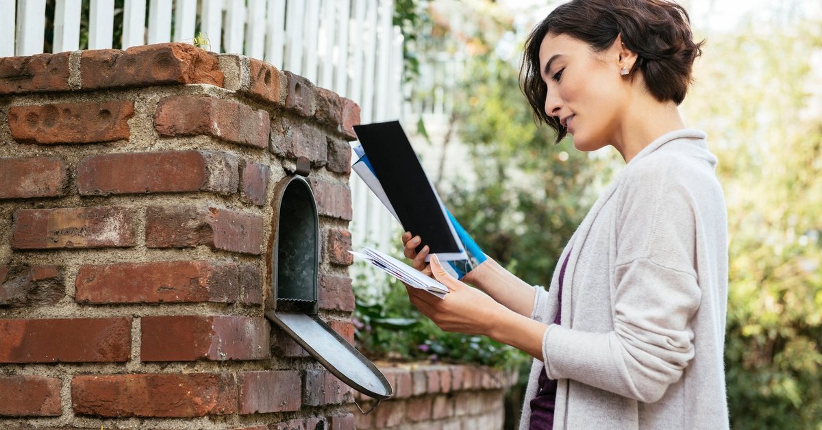 Woman sorting through mail at her mailbox.