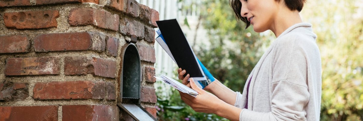 Woman sorting through mail at her mailbox.