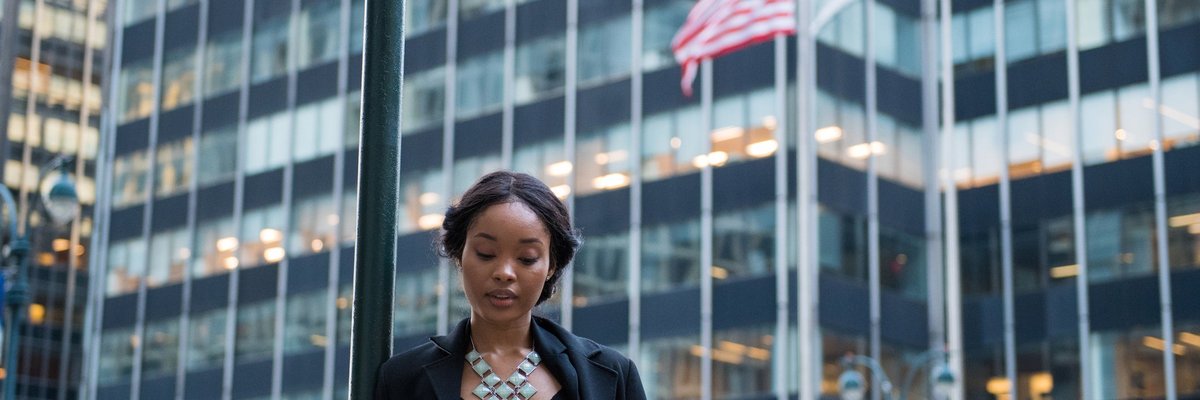 A woman stands outside, looking at her phone.