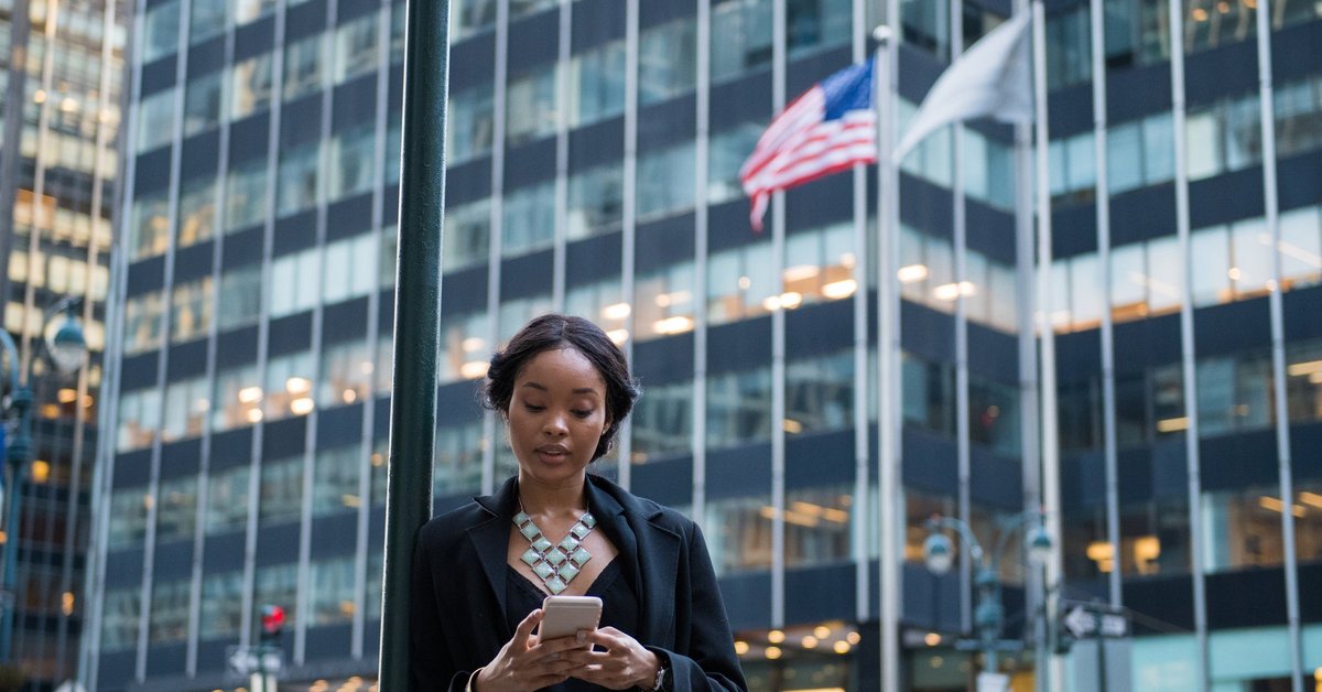 A woman stands outside, looking at her phone.