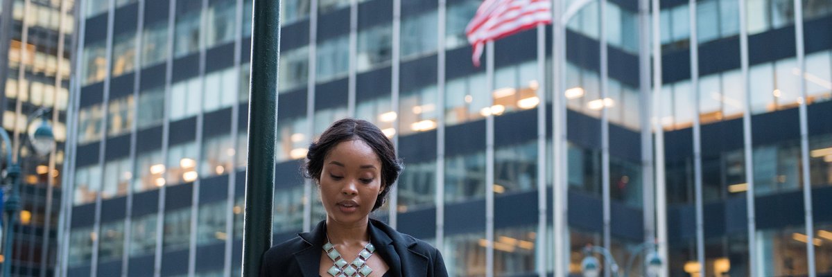 A woman stands outside, looking at her phone.