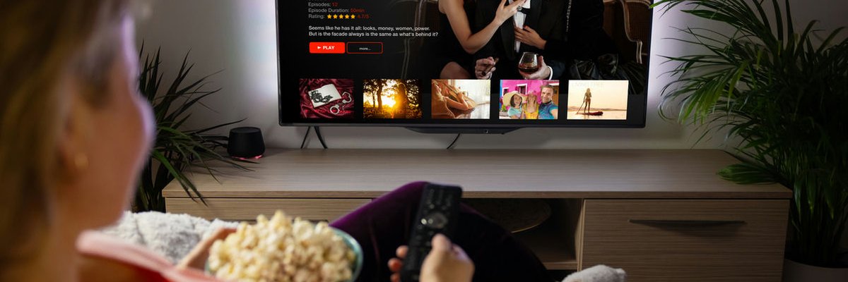 Woman streaming a TV show with popcorn from her couch.