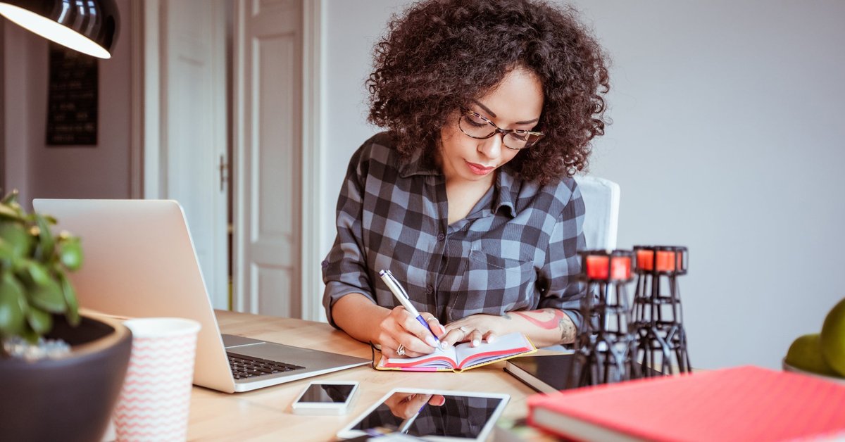 Woman taking notes while using a laptop