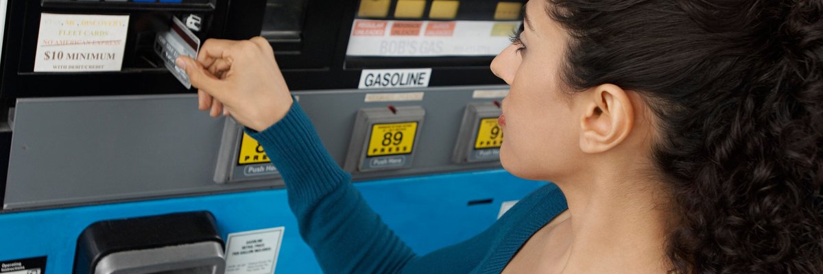 Woman using a credit card to pay at the gas pump.