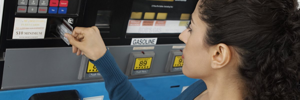 Woman using a credit card to pay at the gas pump.