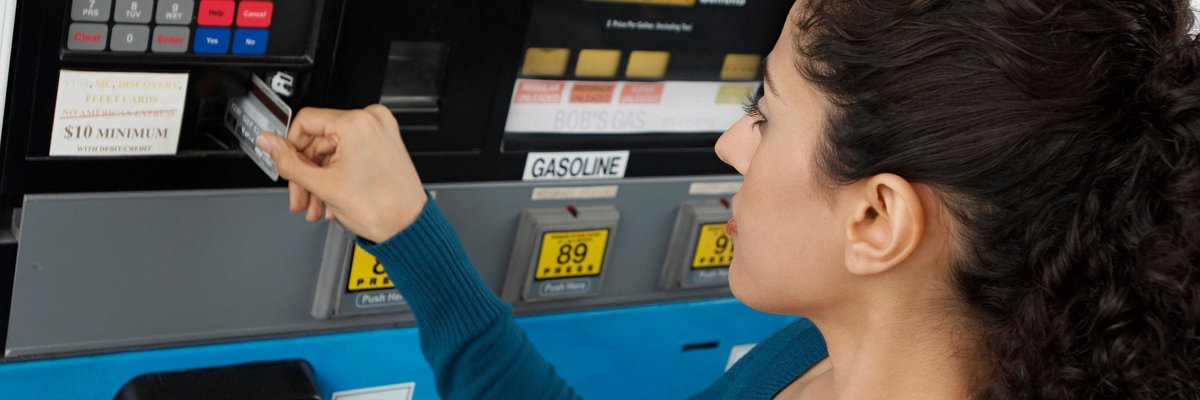 Woman using a credit card to pay at the gas pump.