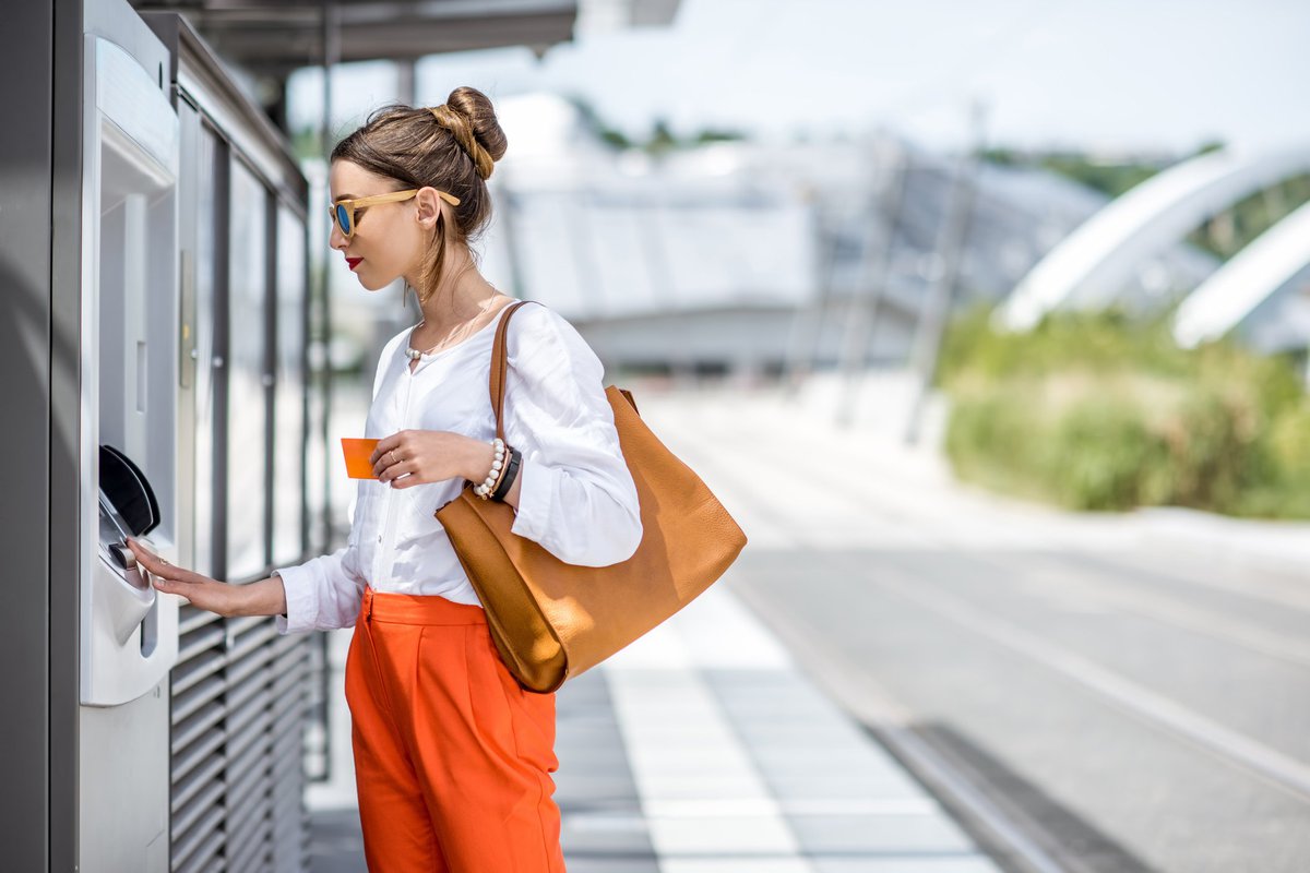 A woman using an ATM on a sunny street.