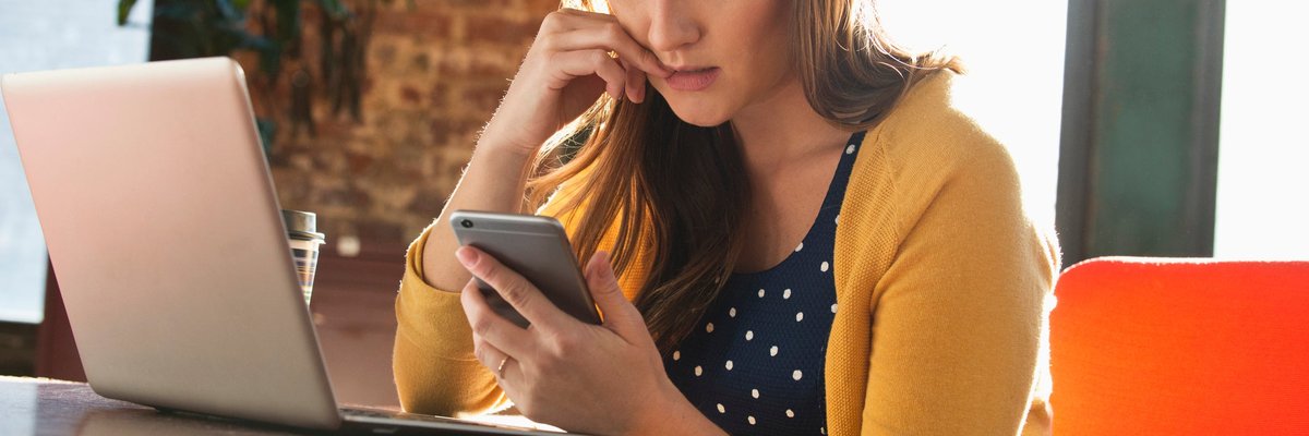Woman using cell phone with concerned look on her face.