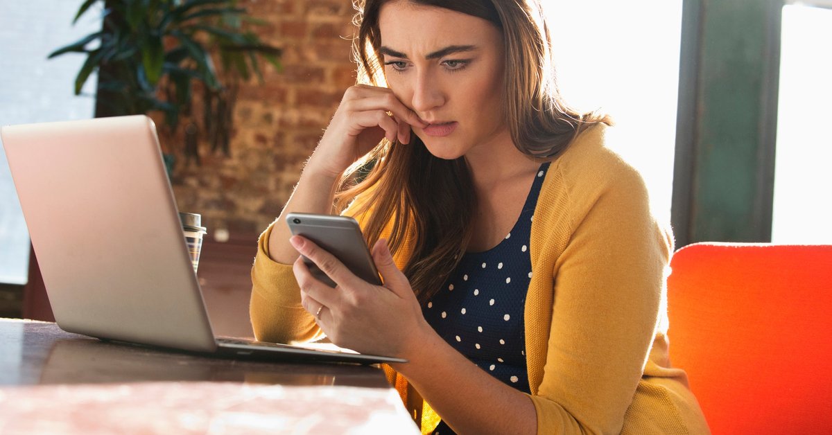 Woman using cell phone with concerned look on her face.