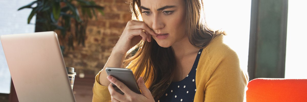 Woman using cell phone with concerned look on her face.