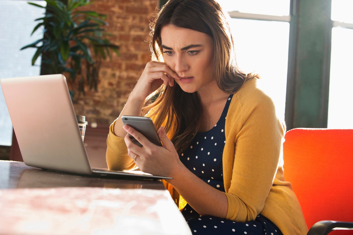 Woman using cell phone with concerned look on her face.