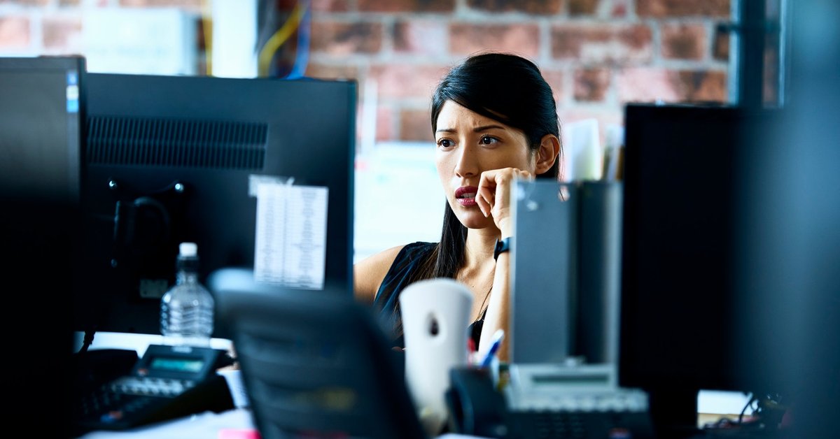 Woman using computer in an office with skeptical look on her face.