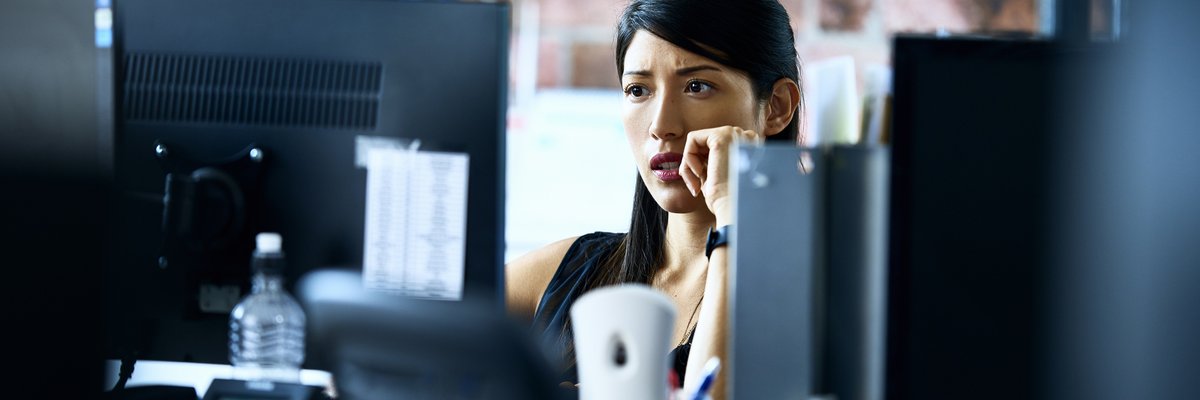 Woman using computer in an office with skeptical look on her face.