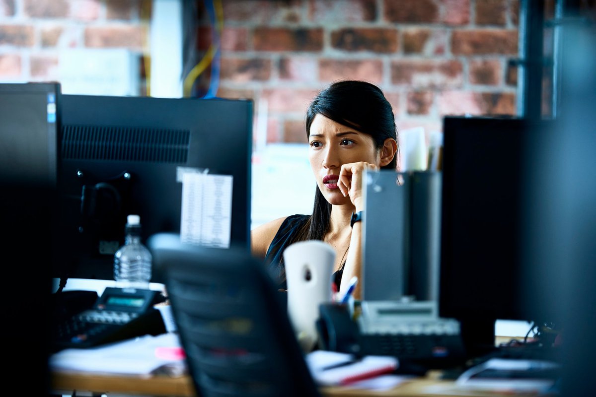 Woman using computer in an office with skeptical look on her face.
