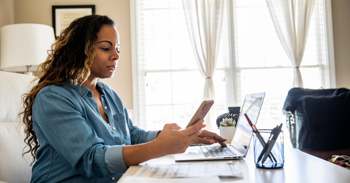 Woman using laptop and smartphone at home