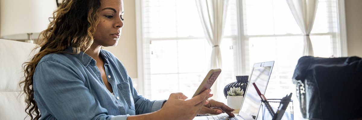 Woman using laptop and smartphone at home
