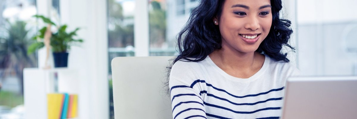 Woman using laptop and smiling.