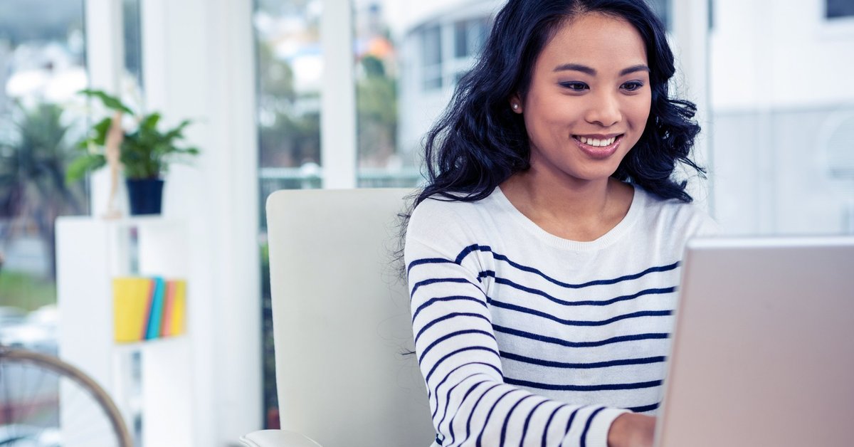Woman using laptop and smiling.