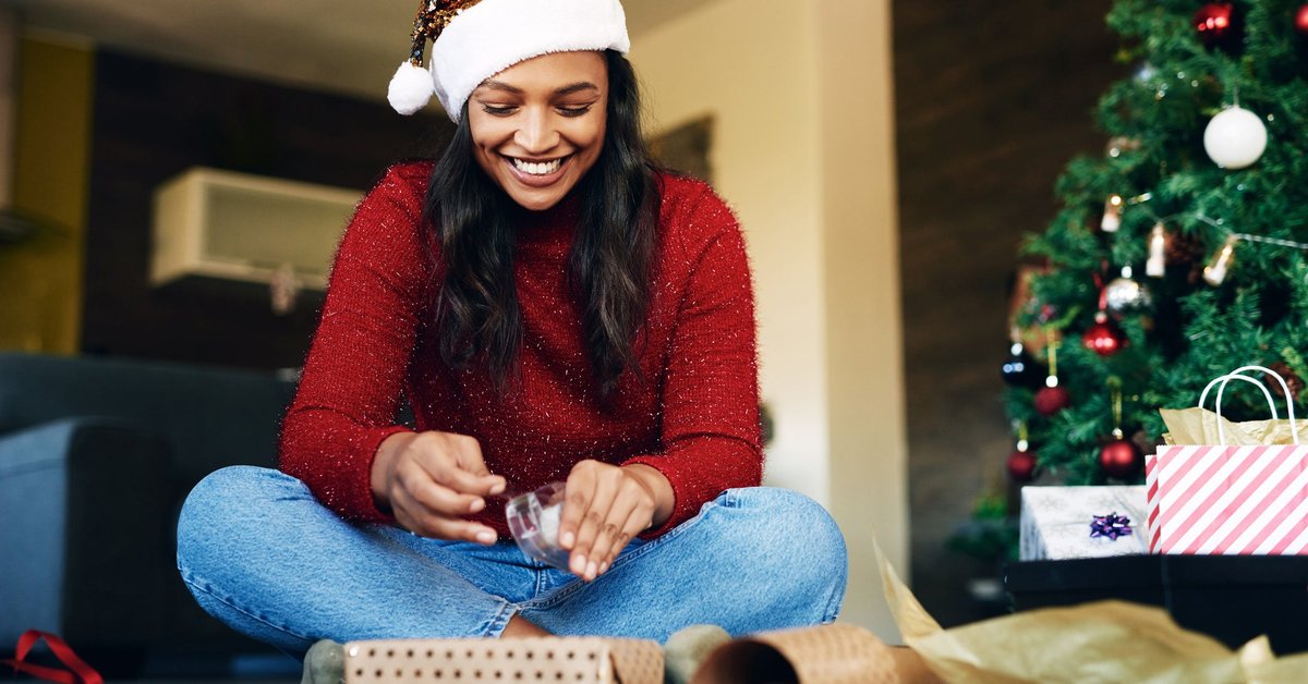Woman wearing Santa hat wrapping gifts.