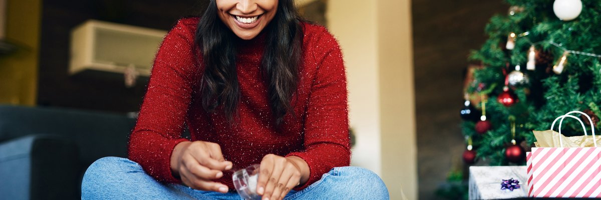 Woman wearing Santa hat wrapping gifts.