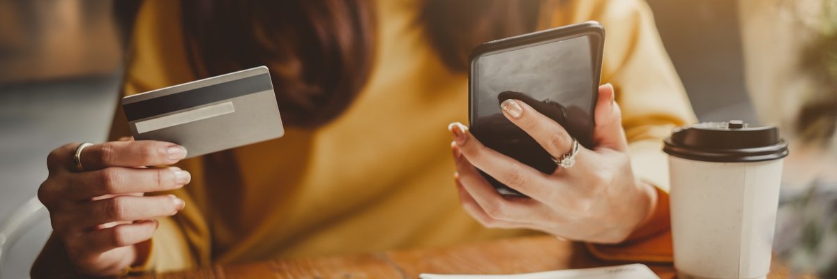 Woman sitting at a table with a credit card, notebook, phone, and coffee