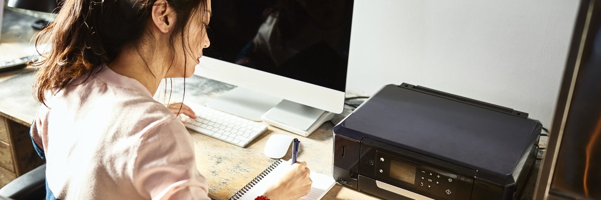 Woman writing in notebook at her home desk