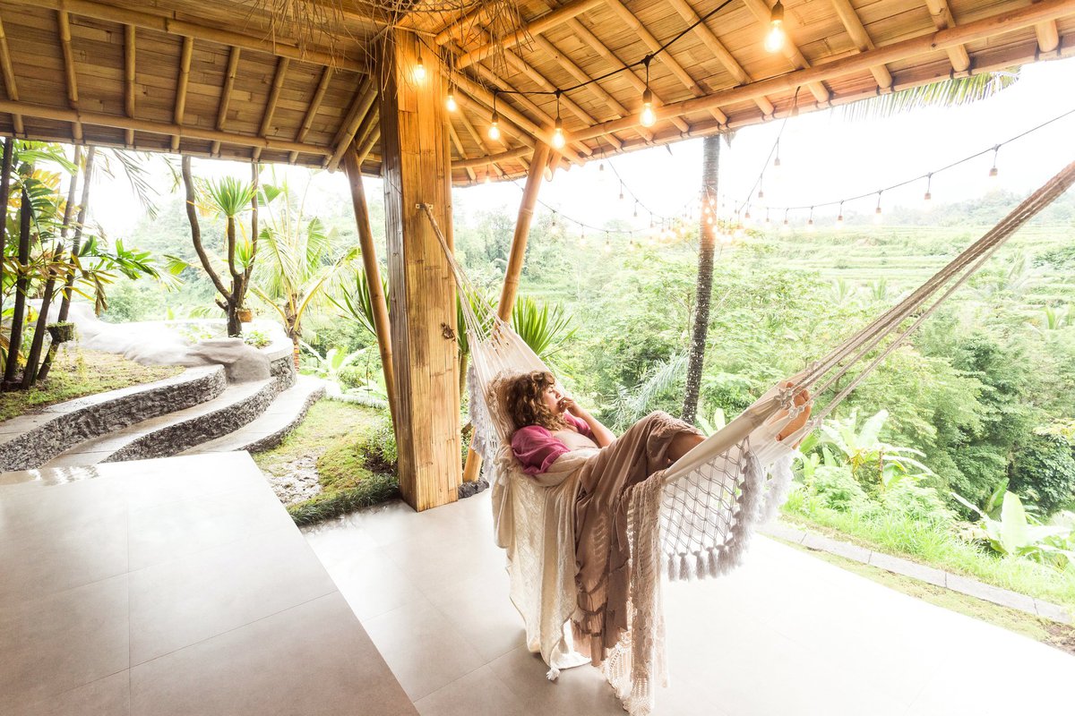 A women in a hammock on a tropical patio.