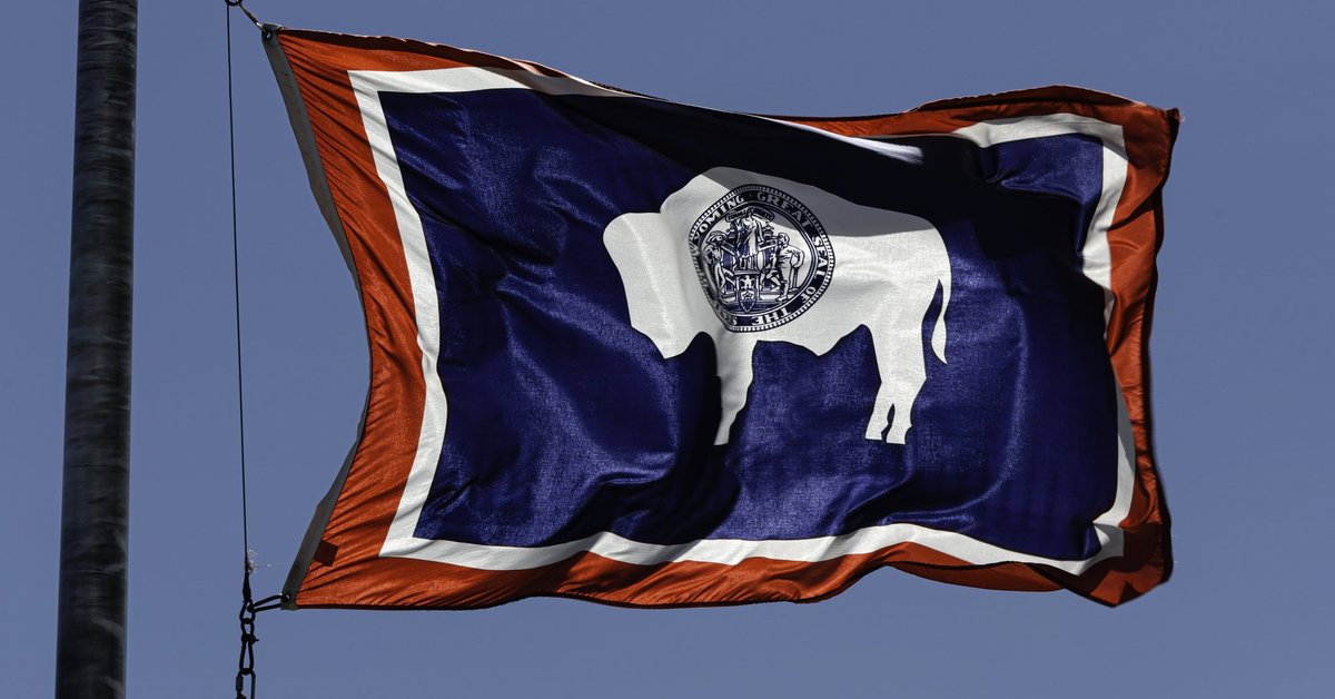 The state flag of Wyoming flying in front of a blue sky.