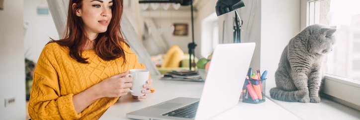 Young Woman With Cat Looking At Laptop