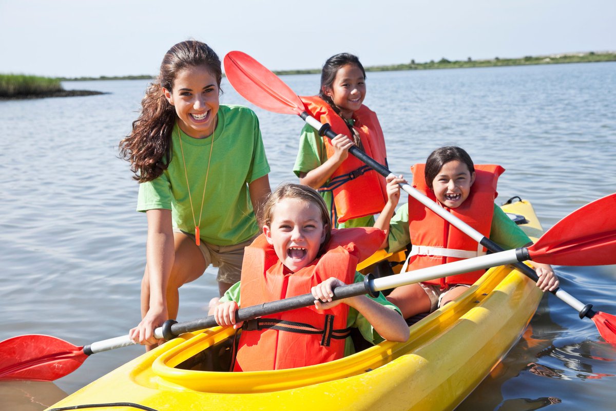 Adult girl helping children in kayak.