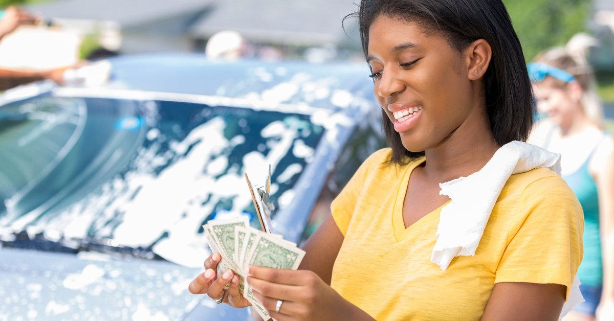 Young adult woman counts cash at car wash