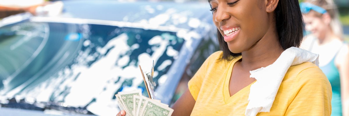 Young adult woman counts cash at car wash