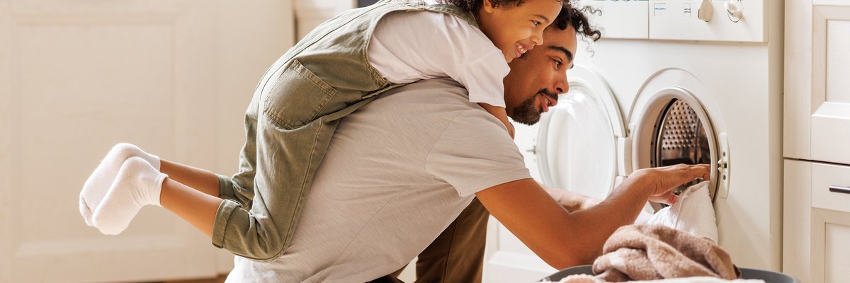 Young child helping father with laundry chores.