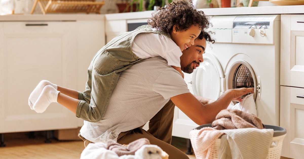 Young child helping father with laundry chores.