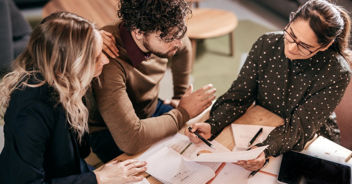 Young couple going over paperwork with female professional.