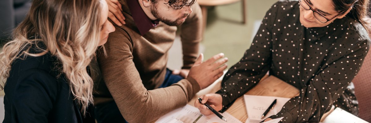 Young couple going over paperwork with female professional.