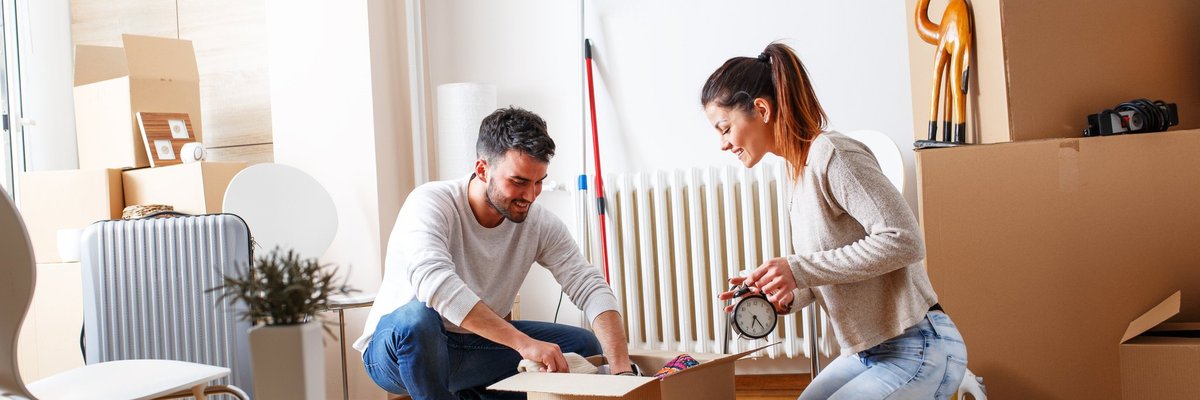 A young couple packing moving boxes in an apartment.